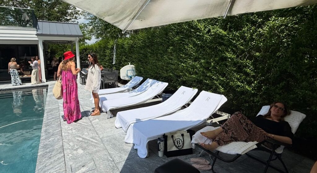 Outdoor mobile massage setup at a poolside event in New Jersey, with white-draped massage tables arranged on a marble patio, surrounded by lush greenery, hosted by Pampered Spirit.